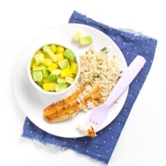 Round white place with crispy white fish, rice and pineapple and avocado salad.