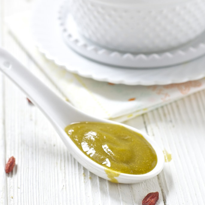 A white spoon filled with a creamy baby food puree. 