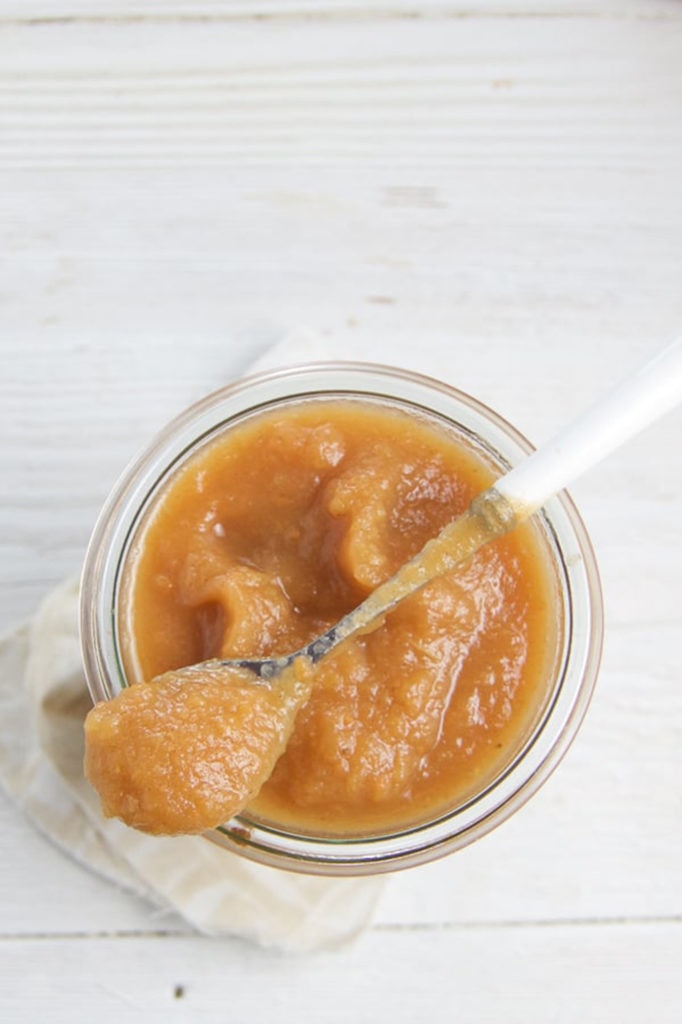 Overhead shot of the applesauce in a jar with a spoon resting ontop. 