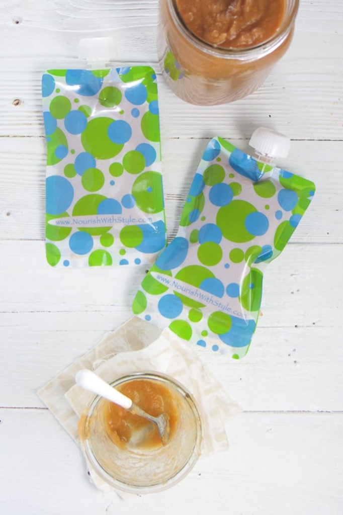 A couple of reusable pouches with an empty jar of carrot applesauce next to it. 
