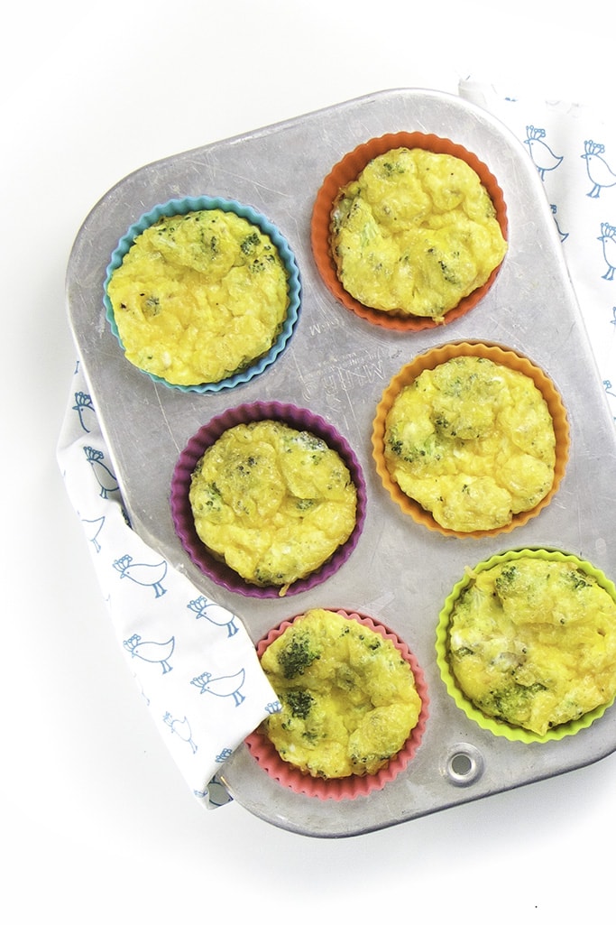 A silver muffin pan filled with broccoli egg cups for baby and toddler. 