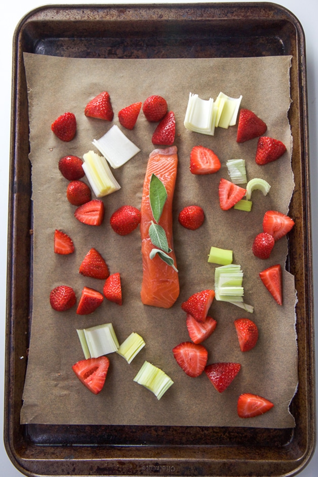 A baking sheet with a spread of strawberries, leeks and salmon for baby food. 