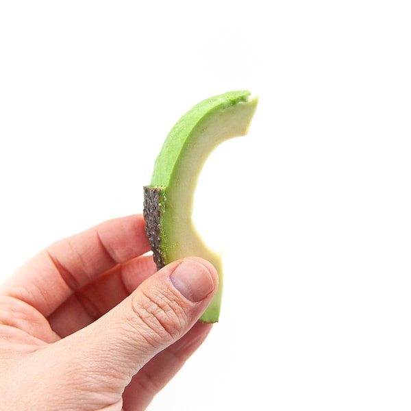 hand holding a slice of avocado