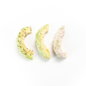 3 slices of avocado coated in crunchy toppings.