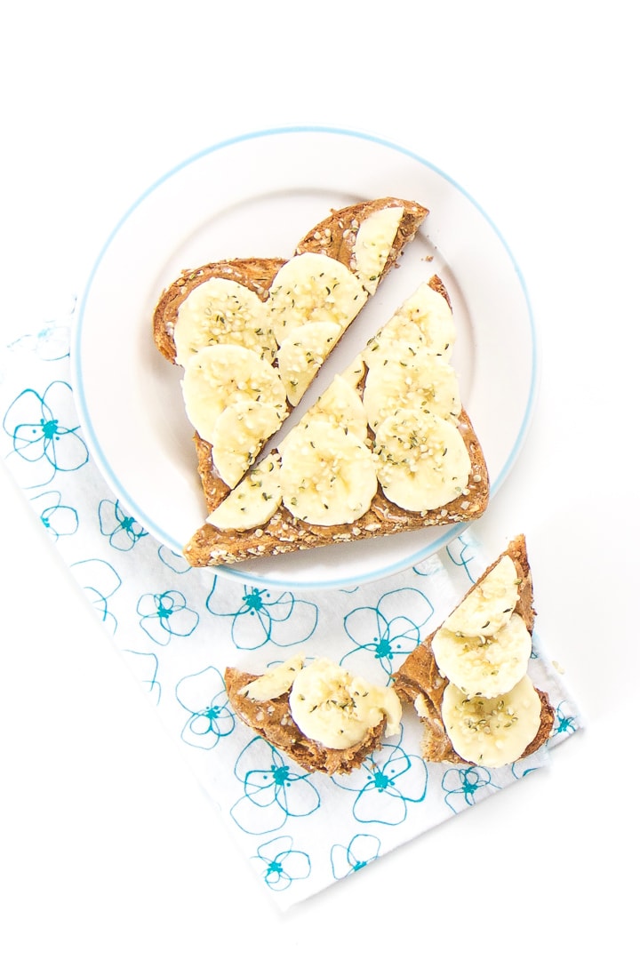 1 round plate with a sliced piece of almond toast for toddler with some torn pieces on a napkin below.