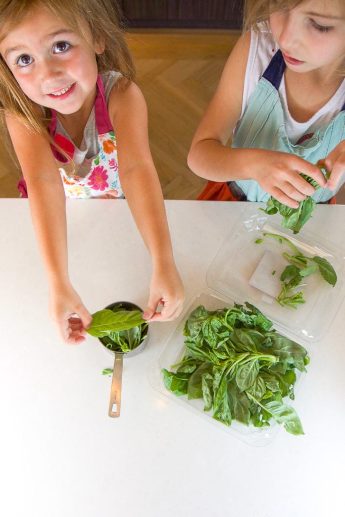 2 girls cooking in a kitchen with basil. 