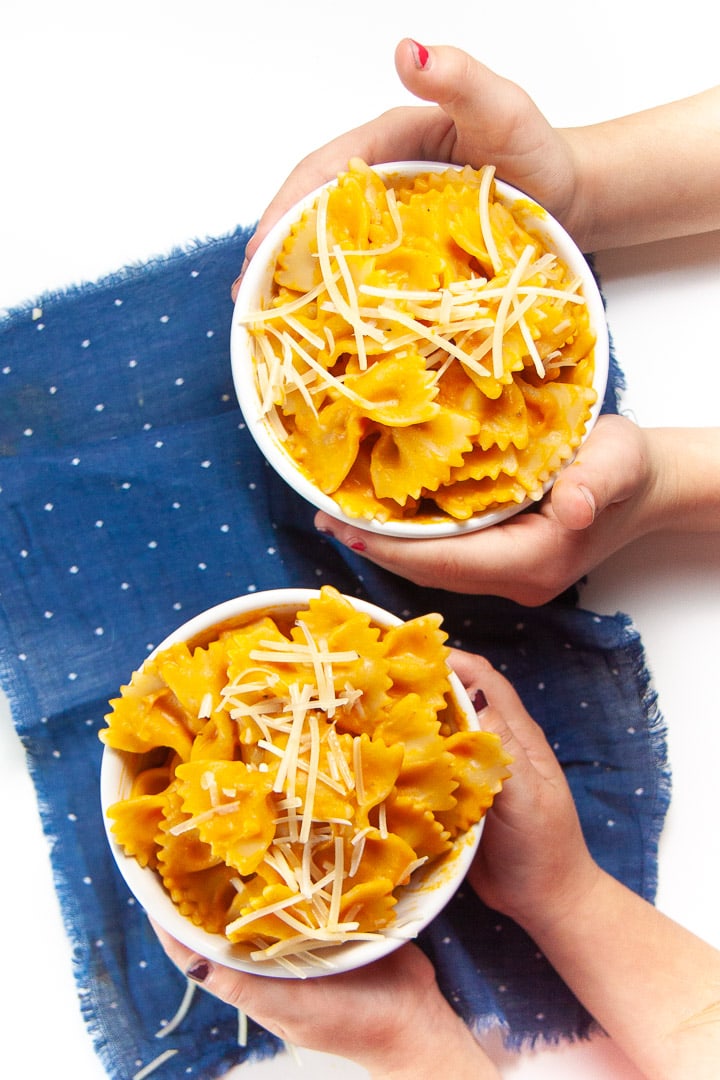 Two sets of hands holding a bowl of family favorite pumpkin pasta.