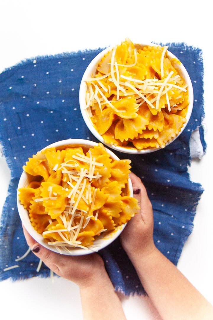 Small hands holding a bowl of family favorite pumpkin pasta.