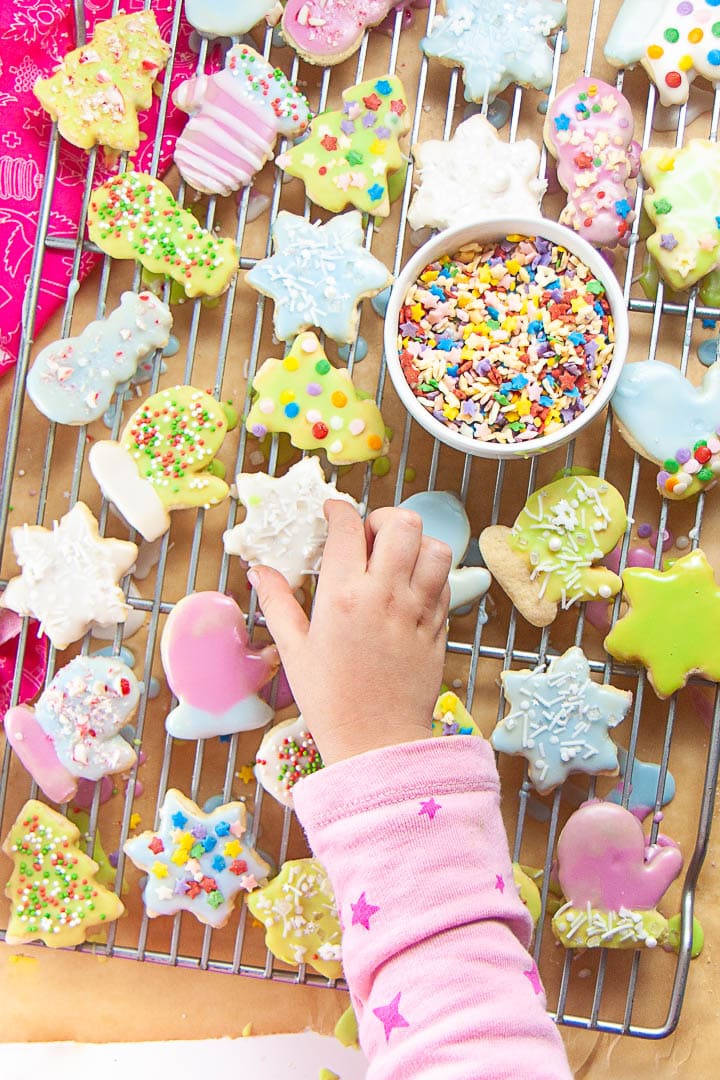 Little hand reaching to get iced sugar cookie.
