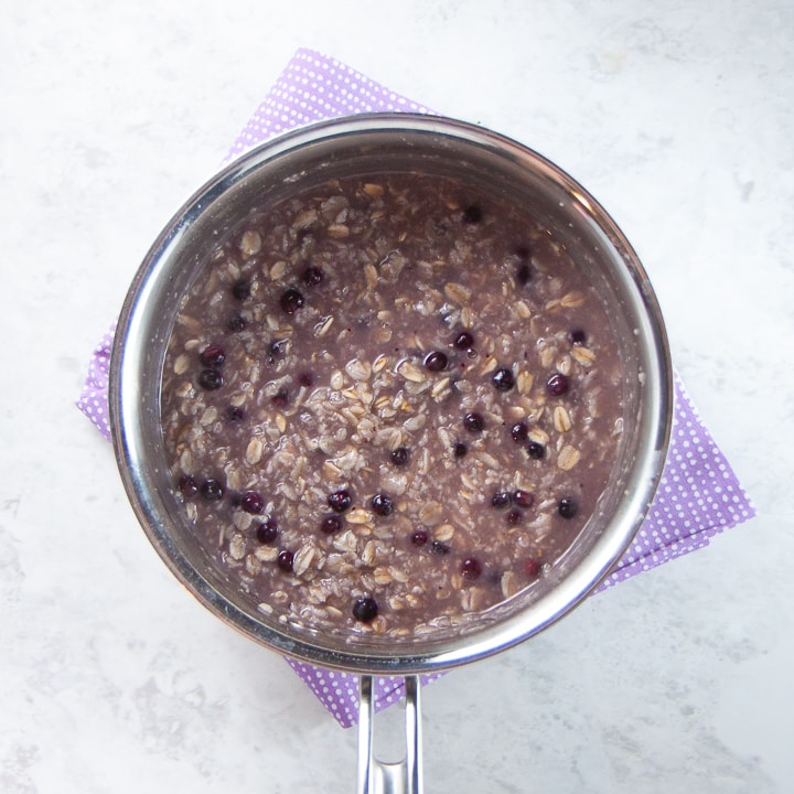 Saucepan filled with oats and blueberries.