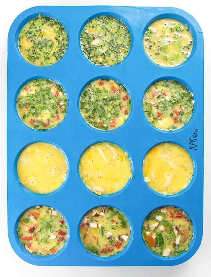 A blue silicone muffin tray with four different combinations of add-ins for egg muffins