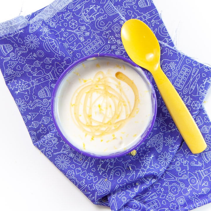 yogurt dip in a purple bowl with honey swirled on top. 