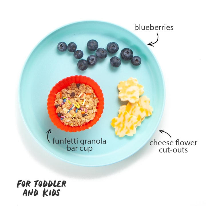 Snack plate with granola bar, cheese flowers and blueberries for toddler or kids. 