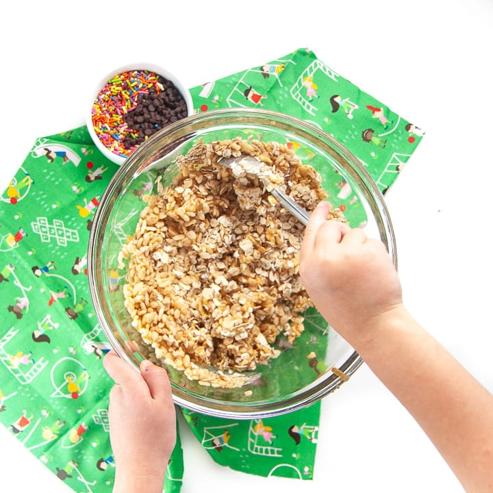 A kid mixing together funfetti granola bites.