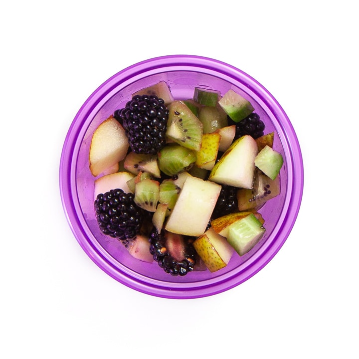 Purple bowl filled with a mixed fruit salad for toddlers and kids.