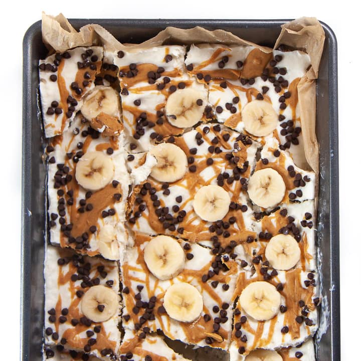 A frozen baking dish of banana, peanut butter and chocolate frozen yogurt bark for toddlers and kids.