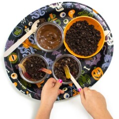 Halloween plate filled with ingredients to make avocado dirt pudding with small hands making it.