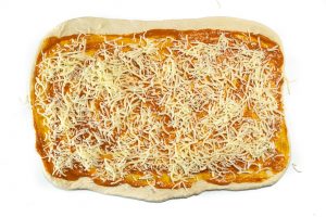 Pizza dough in a rectangle with hidden veggie sauce and cheese.