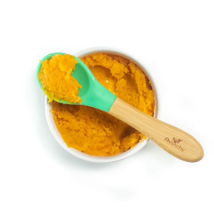 A chunky sweet potato puree in a small white bowl for baby. 