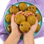 Small kids hands holding 3 mini pumpkin muffins.