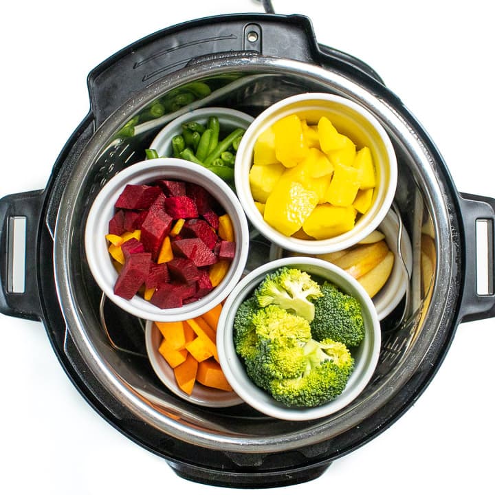 Instant pot filled with ramekins filled with fruits and vegetables for baby food.