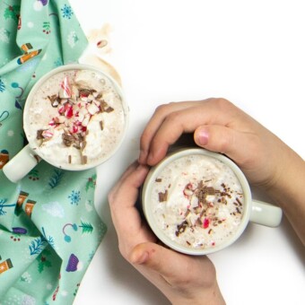 Small hands holding a mug of hot chocolate with toppings!