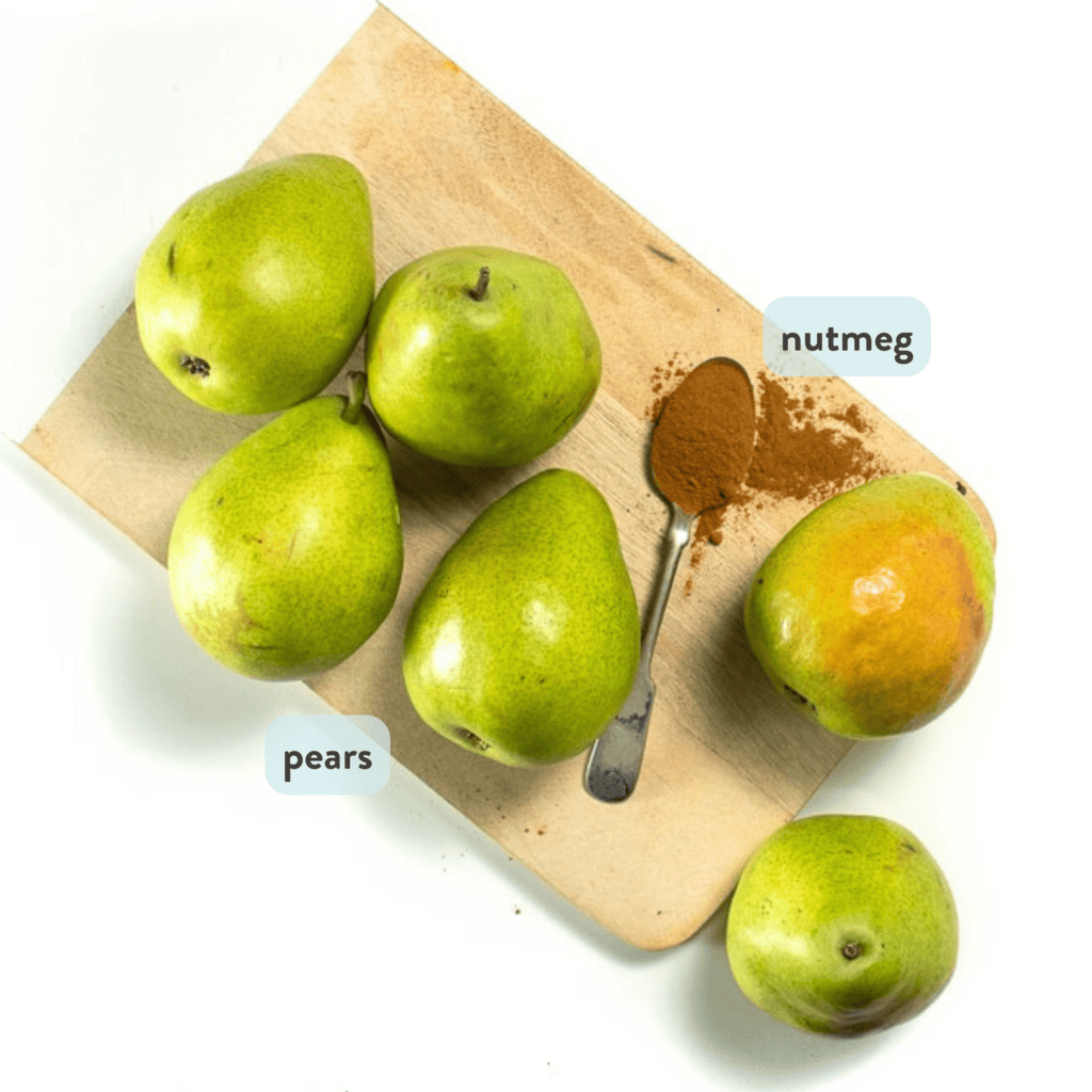 pears and a spoonful of nutmeg are sitting on a wooden cutting board on my white kitchen counter.