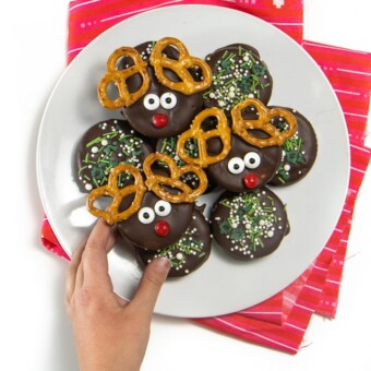 Small kids hand reaching for a reindeer cookie.