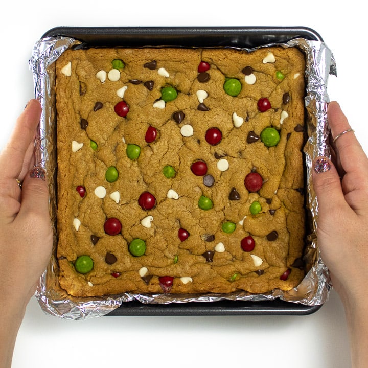 Hands holding a cooled pan of cookie bars.