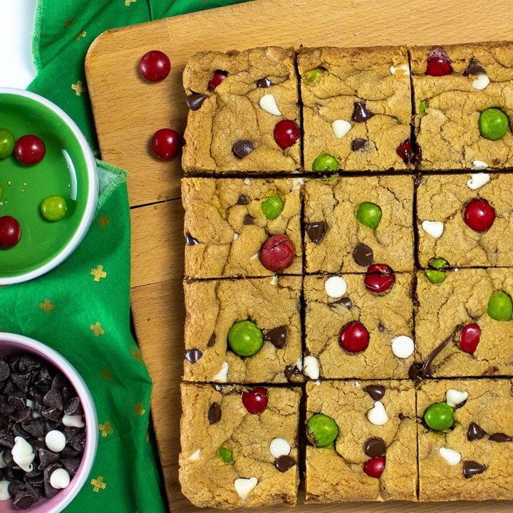 Cookie bars on a cutting board cut into squares.
