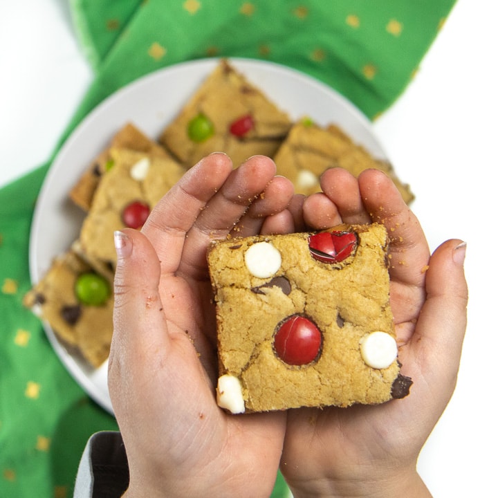 Two small kids hands holding the Christmas Cookie bars in their hands.