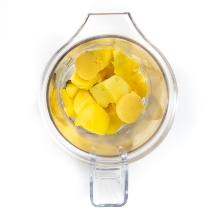 A blender full of mango and egg ready to become a baby puree.