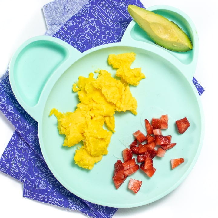 Plate with scrambled eggs and other healthy foods for baby and toddler.