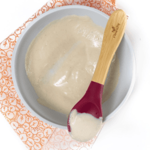 Gray baby bowl full of chicken puree for baby food. The bowl is on a patterned orange and white napkin sitting on my white kitchen counter.