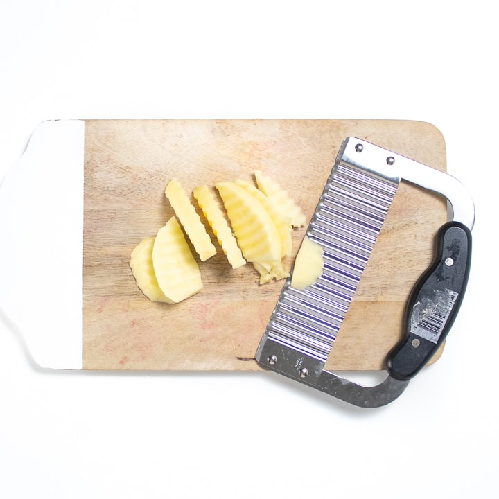 A Cutting board with a waffle knife with sliced apples for baby.