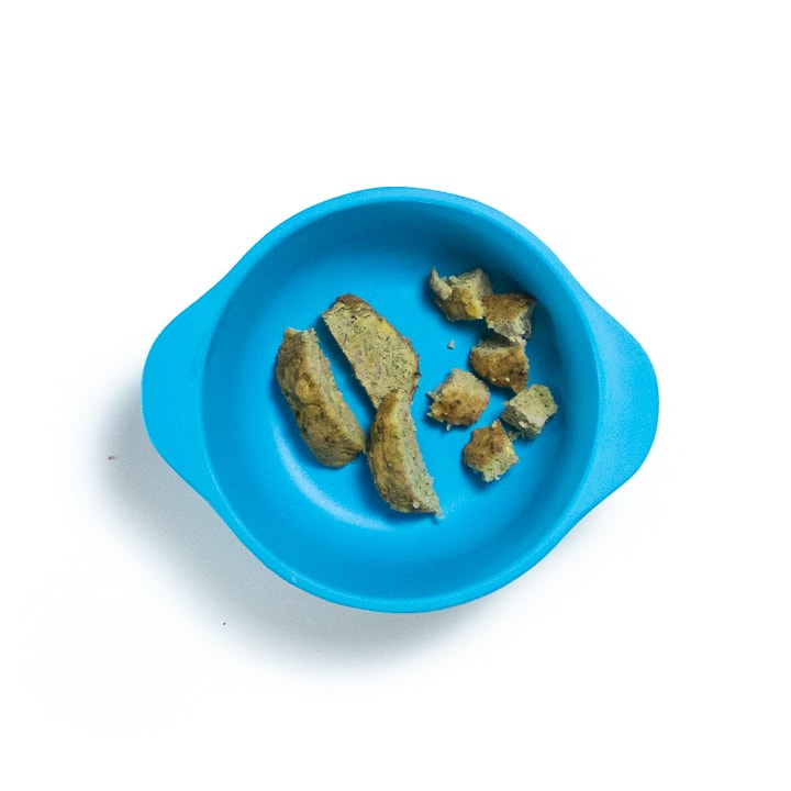 Blue snack bowl of chopped meatballs for baby.