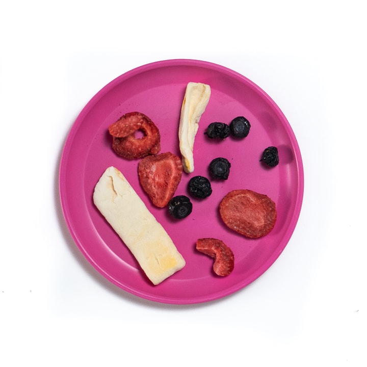 Pink plate with dried fruit on it.