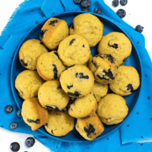 Blue kids plate full of mini blueberry muffins. The plate is sitting on a blue napkin on my kitchen counter.
