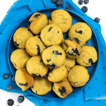 Blue kids plate full of mini blueberry muffins. The plate is sitting on a blue napkin on my kitchen counter.