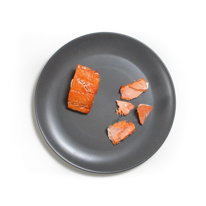 gray plate with cooked salmon for baby both for palmar and pincer grasps.