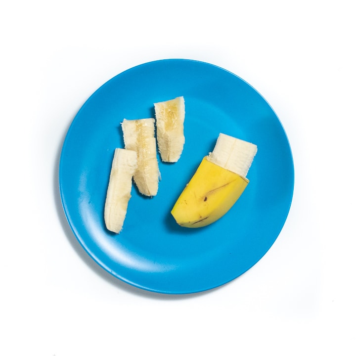 Blue baby plate with a banana peeled and in pieces.