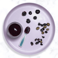 Purple baby plate with self-feeding spoons showing different ways to serve blueberries to baby. The baby plate is sitting on my marble kitchen counter.