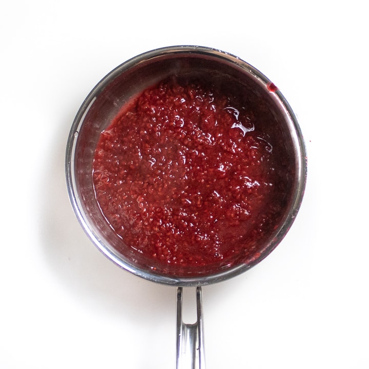 Silver saucepan with cooked down raspberries.