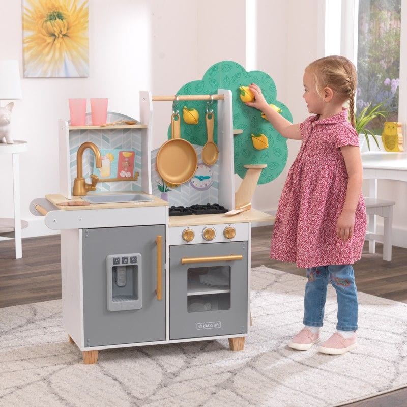 Young playing in front of a gray and white play kitchen.