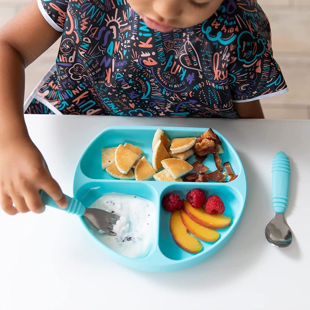 overhead shot of a girl eating off a teal plate with teal utensils 