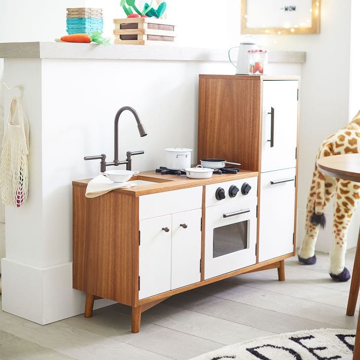 White and wood mid century style play kitchen in a fun kids room.