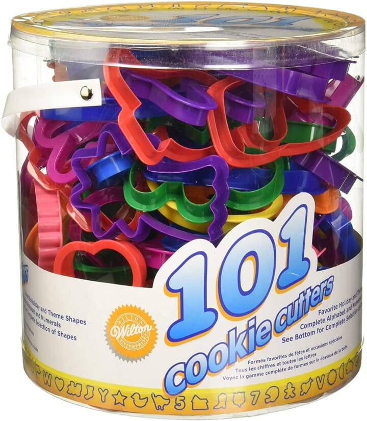 round plastic container with a ton of brighly colored cookie cutters for kids. 
