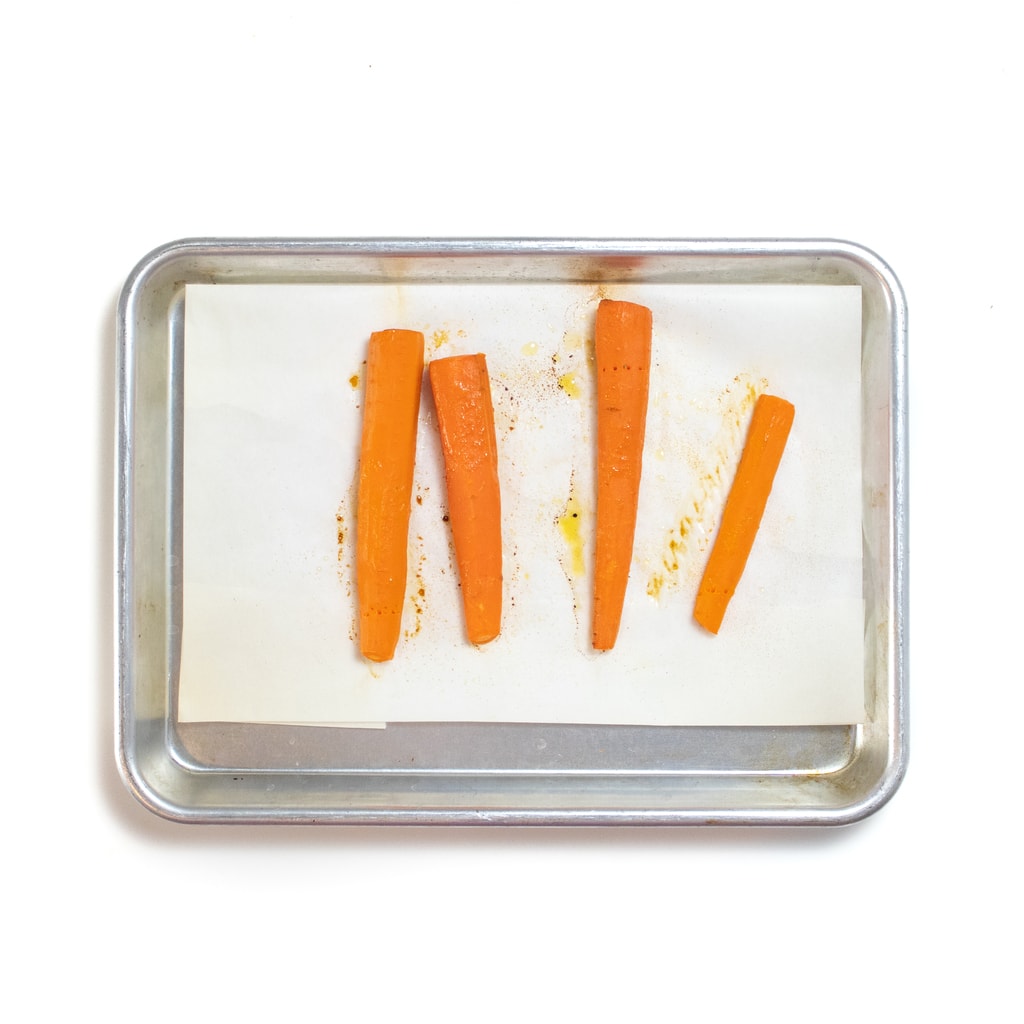 A silver baking sheet with roasted sticks of carrots for baby.