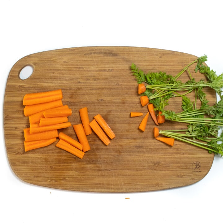 Hey what are you sorry board on a white background with chopped sticks of carrots on it.