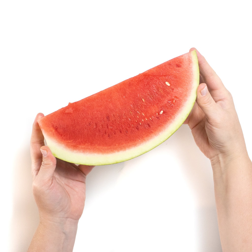 To hold holding a wedge of watermelon against a white background.